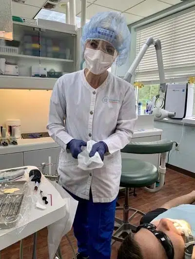 Dental assistant wearing protective haircap and mask
