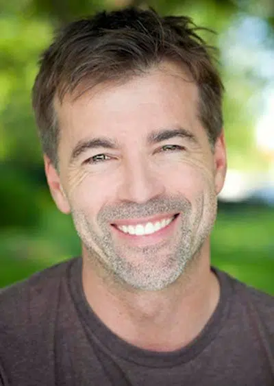 man smiling after mini dental implants restored his smile